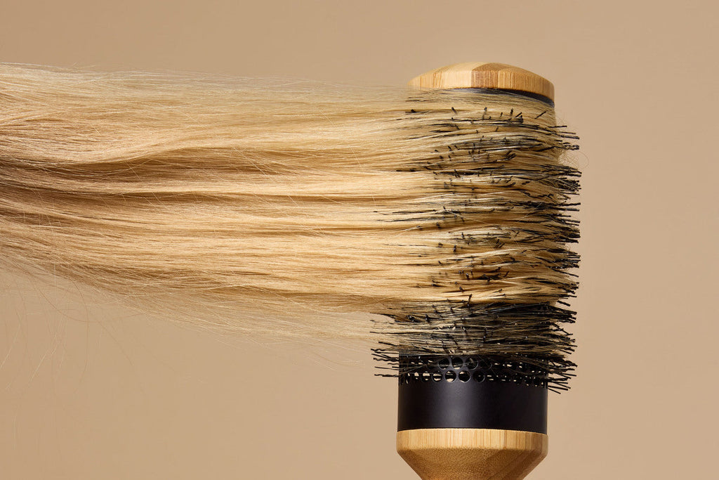 Close-up of a section of long blonde hair wrapped around a boar brush with nylon bristles