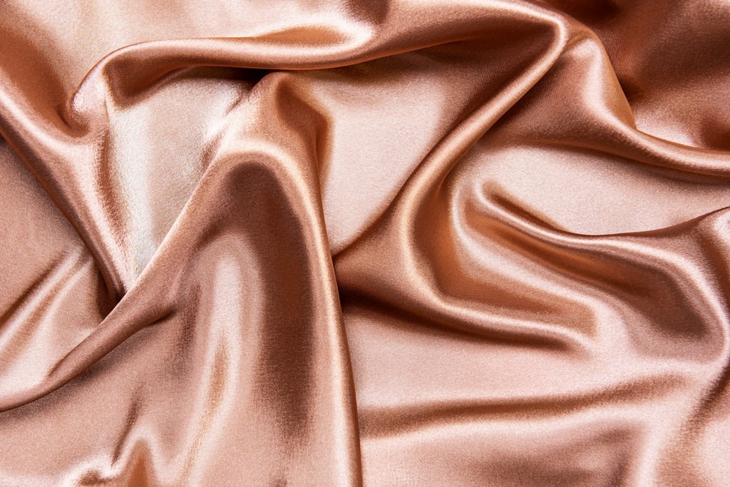 Closeup of a silky pink pillowcase fabric.