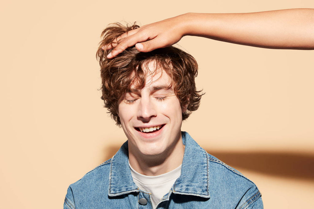 A hand reaches out to ruffle a man's hair