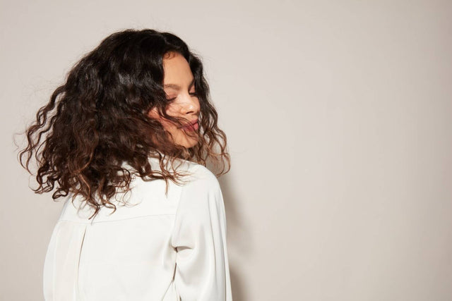 Woman tosses her natural wavy brown hair