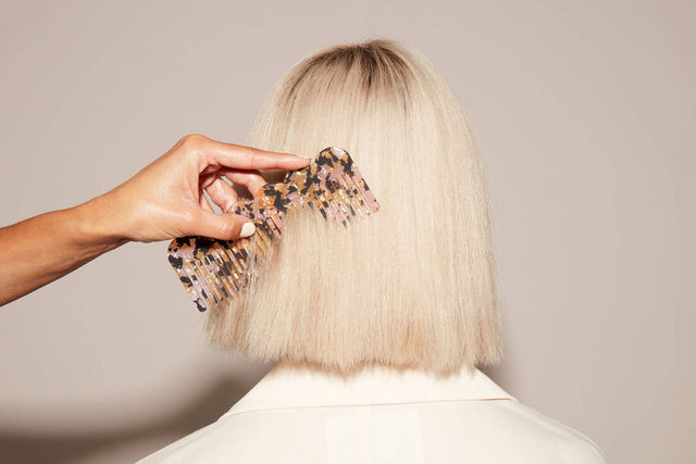 A comb gliding through straight blonde hair