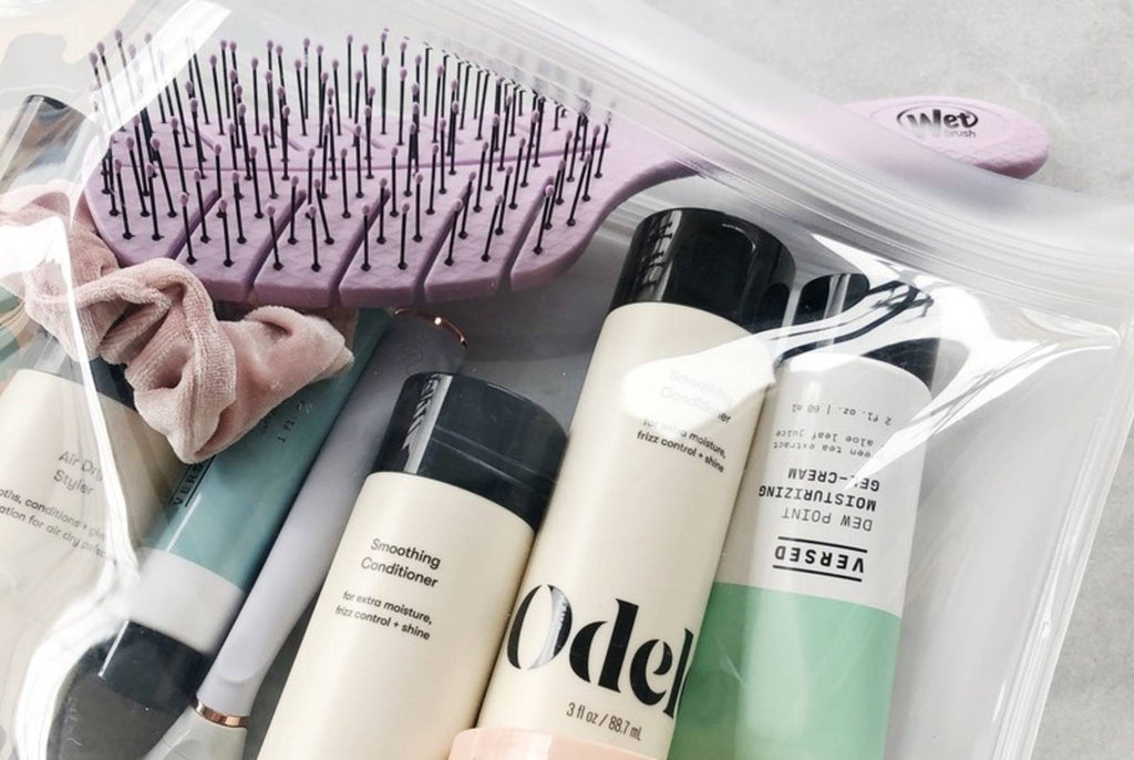 Travel-size Odele hair products sealed in a bag with a hair brush and other accessories
