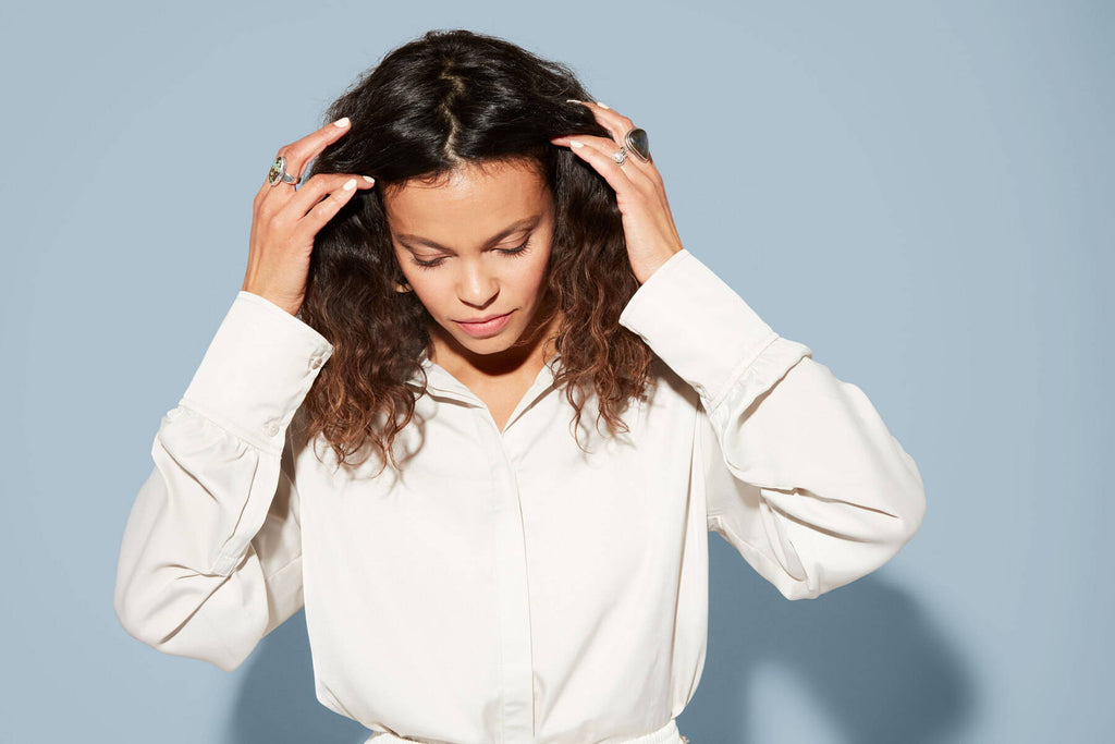 Woman pushes back her thick, wavy brown hair