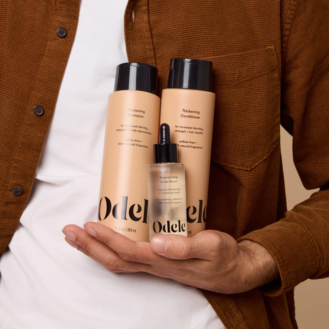 A man holds the Odele Thickening Set in one hand against his chest.