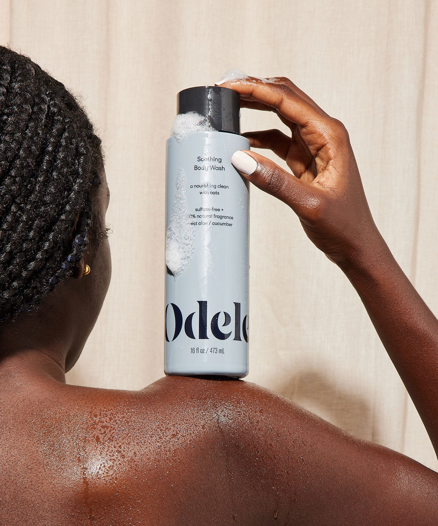 woman holding odele soothing body wash on shoulder