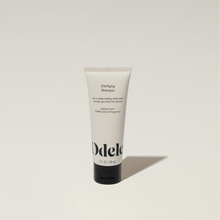 A tube of Odele Clarifying Shampoo stands upright against a plain, light-colored backdrop with the front of the label facing the camera.