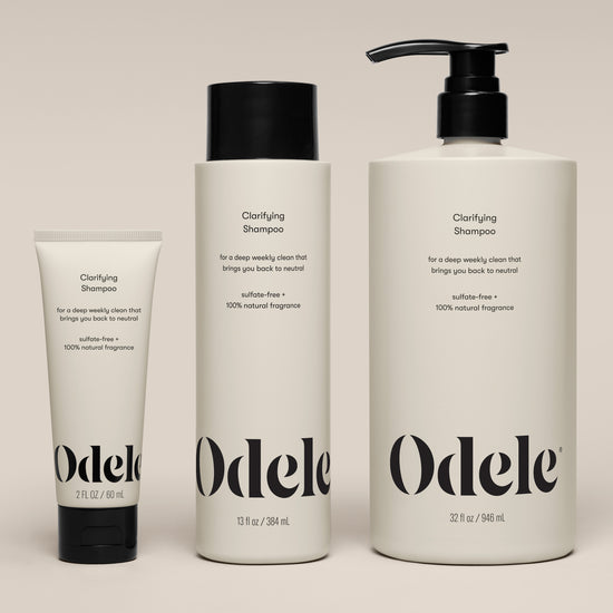 Three bottles of Clarifying Shampoo in 2 fl oz, 13 fl oz, and 32 fl oz sizes stand side by side against a neutral background. The white bottles feature black text and caps.