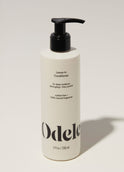 A bottle of Odele Leave-in Conditioner stands upright against a plain, light-colored backdrop with the front of the label facing the camera.