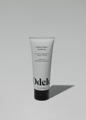 A tube of Odele Moisture Repair Conditioner stands upright against a plain, light-colored backdrop with the front of the label facing the camera.