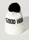 The Good Hair Day Winter Hat is a white knit beanie featuring a black pom-pom and GOOD HAIR in bold black text on the front. This limited-edition item is shown against a simple white background.
