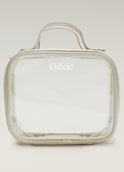The Going Places Travel Bag is a clear, square-shaped essentials bag with beige trim and a top handle. Odele is printed in white on the front. Ideal for mini shampoos, it’s shown against a soft, neutral gradient background.