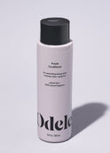 A bottle of Odele Purple Conditioner stands upright against a plain, light-colored backdrop with the front of the label facing the camera.