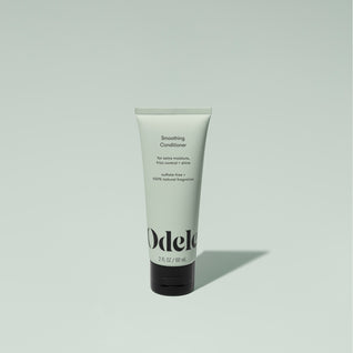 A tube of Odele Smoothing Conditioner stands upright against a plain light green backdrop with the front of the label facing the camera.