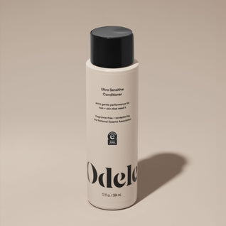 A bottle of Odele Ultra Sensitive Conditioner stands upright against a plain, light-colored backdrop with the front of the label facing the camera.