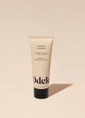 A tube of Odele Volumizing Conditioner stands upright against a plain, light orange backdrop with the front of the label facing the camera.