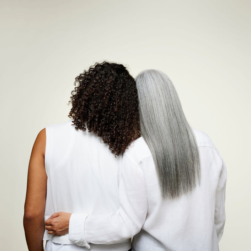 Person with gray hair leaning on person with curly hair