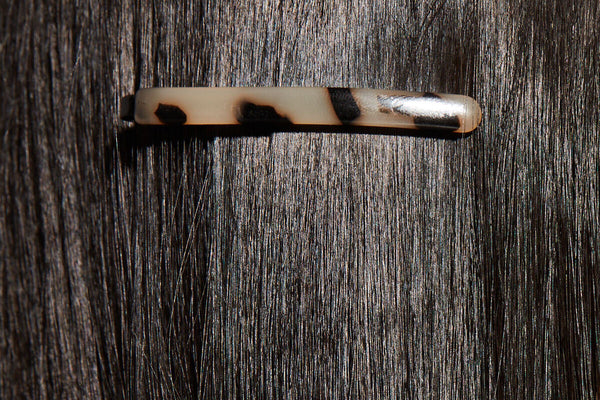 Close-up of shiny black hair with a tortoiseshell hair clip.