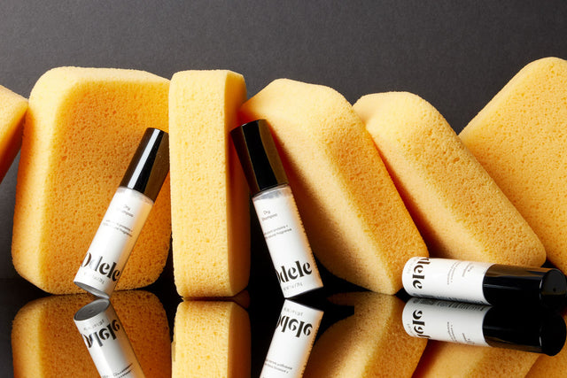 Bottles of Odele Dry Shampoo next to big yellow sponges