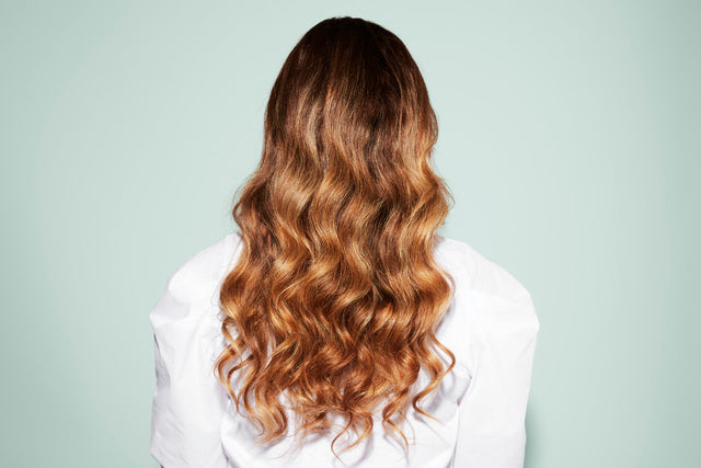 Back view of a person with long, wavy auburn hair 