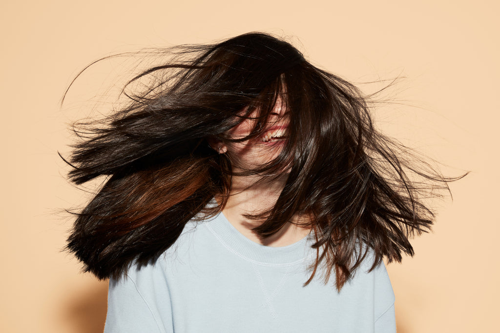 Girl with long straight brown hair blowing wildly in the wind