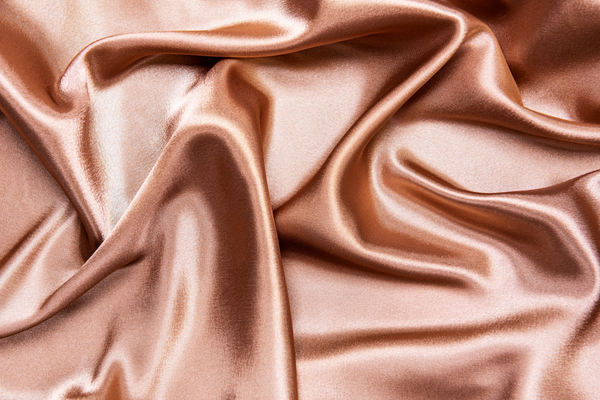 Closeup of a silky pink pillowcase fabric. 