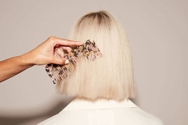 A comb gliding through straight blonde hair 