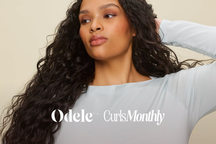 A woman with long, dark, curly hair poses with one hand behind her head, wearing a light blue top. The text Odele x Curls Monthly is overlaid on the image.