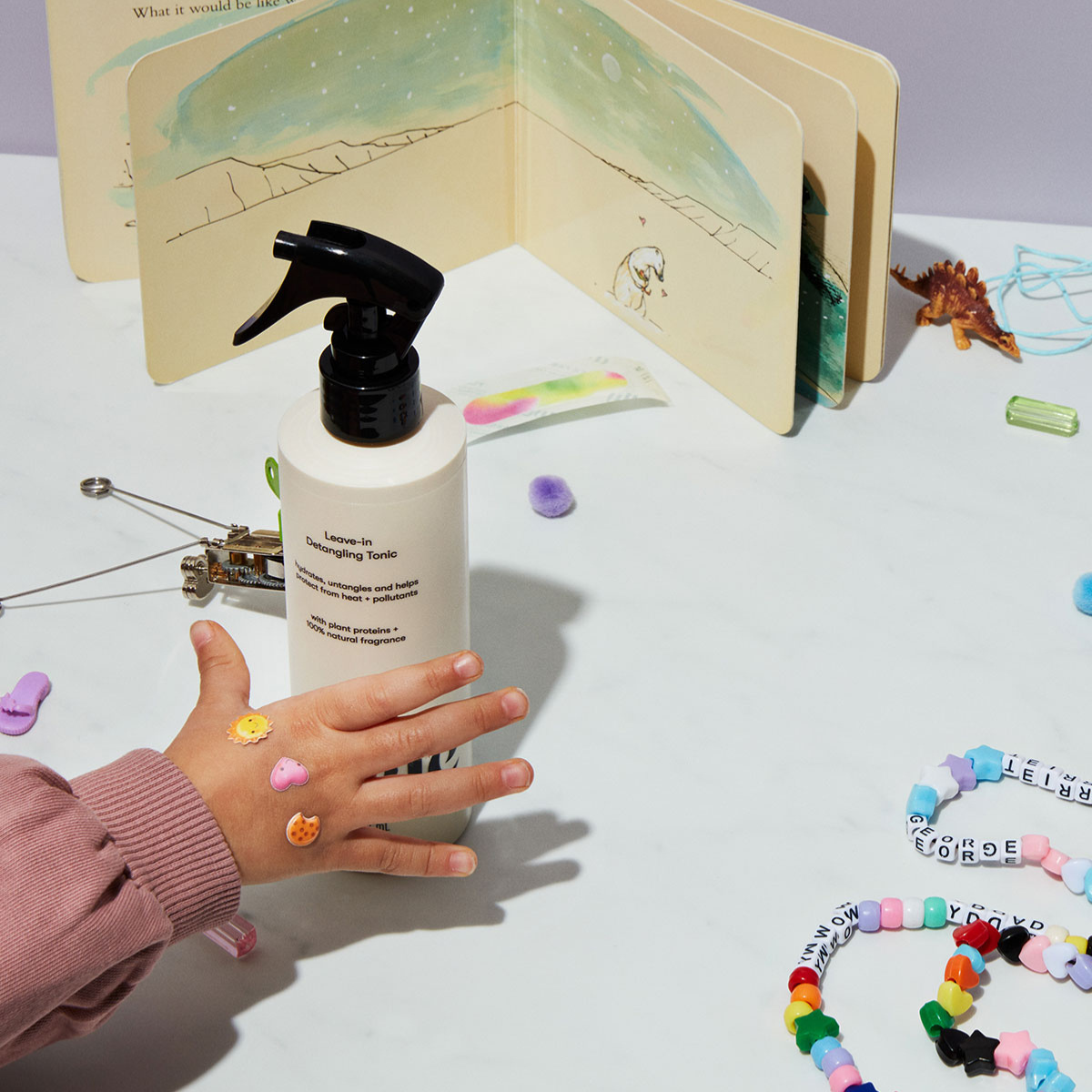 Child's hand reaching for detangling tonic