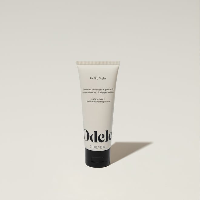 A tube of Odele Air Dry Styler stands upright against a plain, light-colored backdrop with the front of the label facing the camera.