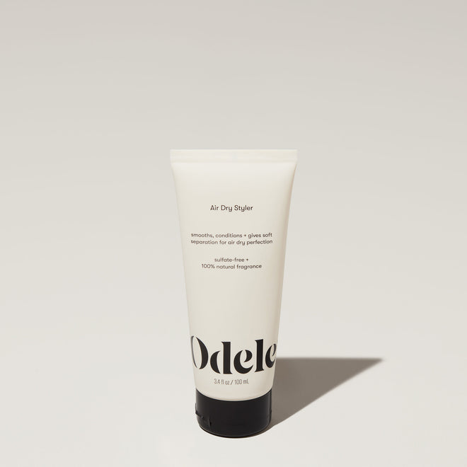 A tube of Odele Air Dry Styler stands upright against a plain, light-colored backdrop with the front of the label facing the camera.