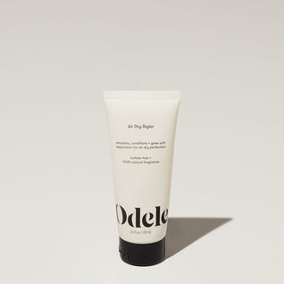 A tube of Odele Air Dry Styler stands upright against a plain, light-colored backdrop with the front of the label facing the camera.