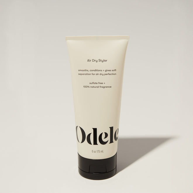 A tube of Odele Air Dry Styler stands upright against a plain, light-colored backdrop with the front of the label facing the camera.