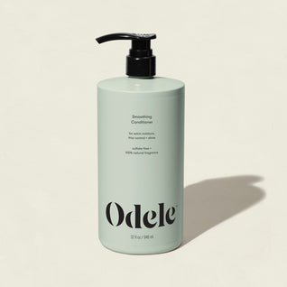 A light green bottle of Smoothing Conditioner Bulk with a black pump, labeled sulfate-free and 100% natural fragrance for frizz control, is shown on a neutral background with a right-side shadow.