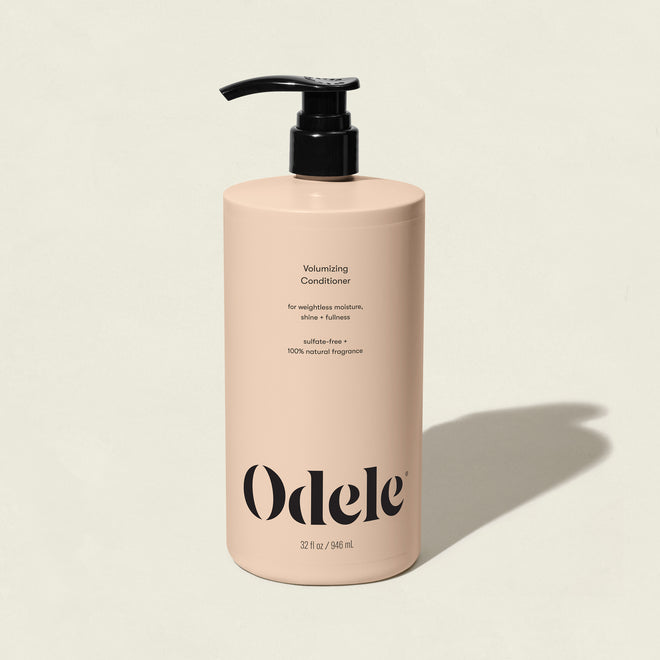 A beige bottle of Volumizing Conditioner Bulk with a black pump sits on a light background. The label highlights sulfate-free and 100% natural fragrance, offering weightless moisture and shine in a large 32 fl oz (946 ml) size.