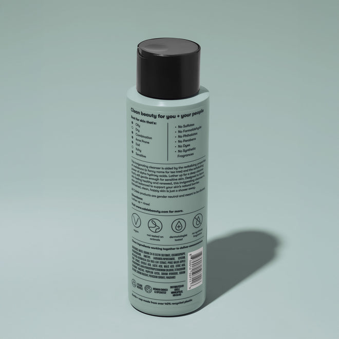 A bottle of Odele Clarifying Body Wash stands upright against a plain, light-colored backdrop with the back of the label facing the camera.