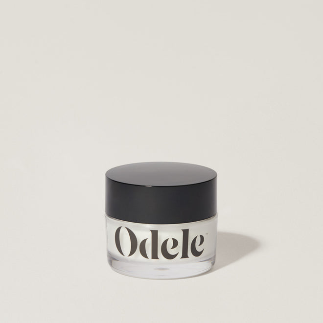 A jar of Odele Cream Pomade stands upright against a plain, light-colored backdrop with the front of the label facing the camera.