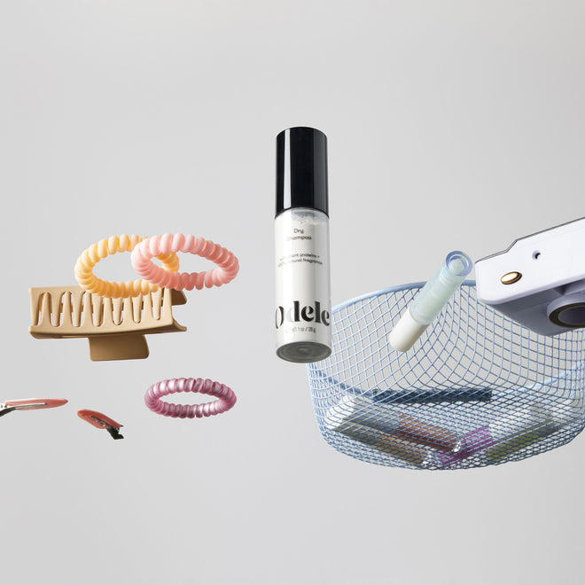 The Odele Dry Shampoo sits among assorted hair accessories on a clear surface above the camera.
