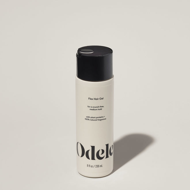 A bottle of Odele Flex Hair Gel stands upright against a plain, light-colored backdrop with the front of the label facing the camera.