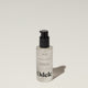 A bottle of Odele Hair Oil stands upright against a plain, light-colored backdrop with the front of the label facing the camera.