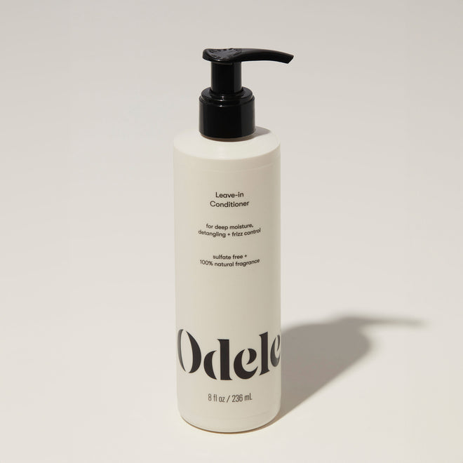 A bottle of Odele Leave-in Conditioner stands upright against a plain, light-colored backdrop with the front of the label facing the camera.