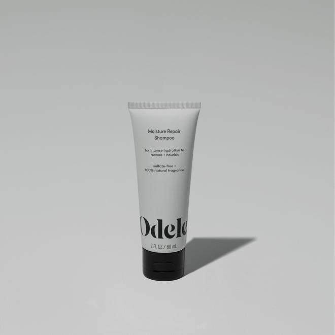 A tube of Odele Moisture Repair Shampoo stands upright against a plain, light-colored backdrop with the front of the label facing the camera.