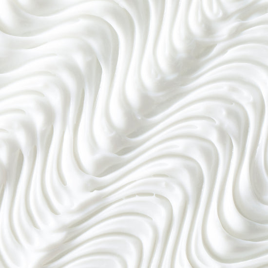 Close-up of Odele Beauty’s Moisture Repair Conditioner Mini: a white, creamy formula with smooth, wavy swirls—like whipped cream—for luxurious hydration and a soft, airy look.