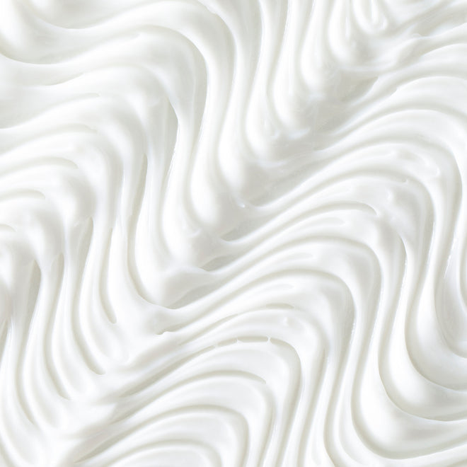 Close-up of Odele Beauty’s Moisture Repair Conditioner Mini: a white, creamy formula with smooth, wavy swirls—like whipped cream—for luxurious hydration and a soft, airy look.