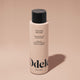A bottle of Odele Moisturizing Body Wash stands upright against a plain, light orange backdrop with the front of the label facing the camera.