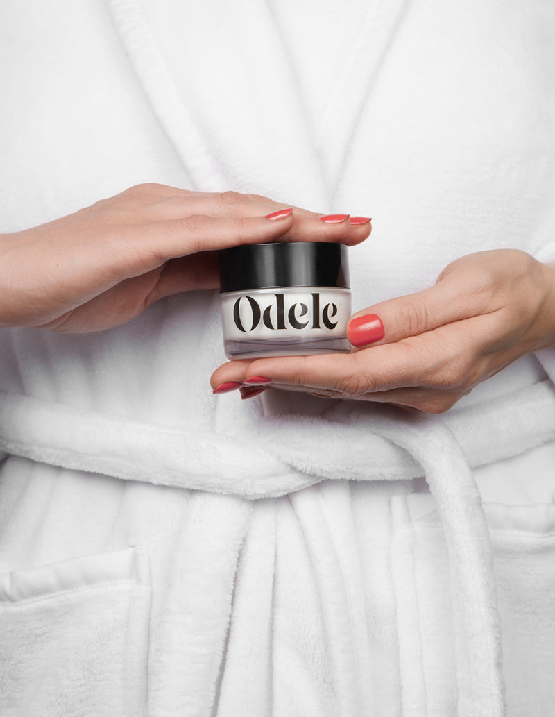 person in robe holding cream pomade bottle
