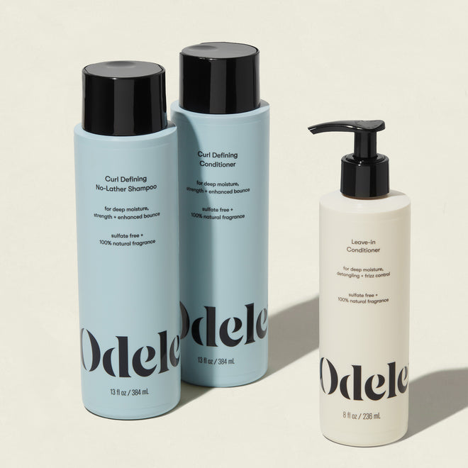The Curl Defining Set by Odele includes two large blue bottles for hydrating curls—Curl Defining No-Lather Shampoo and Curl Defining Conditioner—plus a smaller pump bottle of Leave-In Conditioner.
