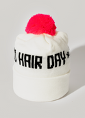 The Good Hair Day Winter Hat is a white knit beanie with a bright pink pom-pom and black HAIR DAY text on the front, designed for quality comfort by winter experts.