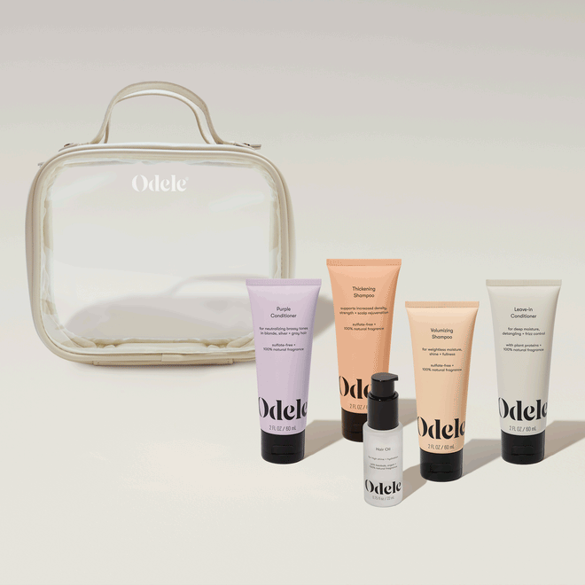 Five Odele Essentials—four mini tubes and one mini pump bottle—are arranged in front of the Going Places Travel Bag, which is clear with beige trim, all set against a neutral background.
