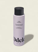 A bottle of Odele Purple Conditioner with a black cap, designed to nourish blonde hair and neutralize brassiness, is shown on a plain off-white background.