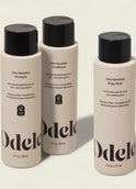 Three beige bottles from the Odele Ultra Sensitive Set—shampoo, conditioner, and body wash—stand upright on a light background. Their labels highlight that they are ultra sensitive and fragrance-free.